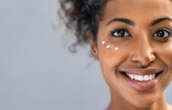 cheerful young Afro-American woman with dots of face cream under her eyes