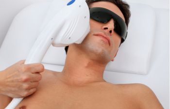 man in laser safety goggles in spa salon undergoing laser hair removal procedure